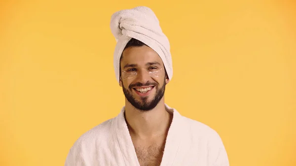 Hombre feliz en parches para los ojos albornoz y toalla aislada en amarillo - foto de stock