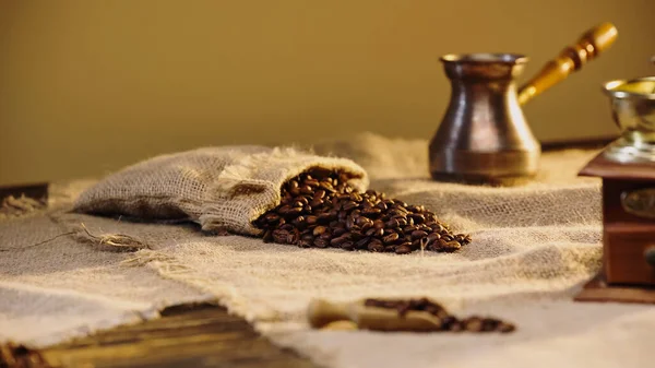 Grains de café dans un sac en toile près de la cafetière — Photo de stock