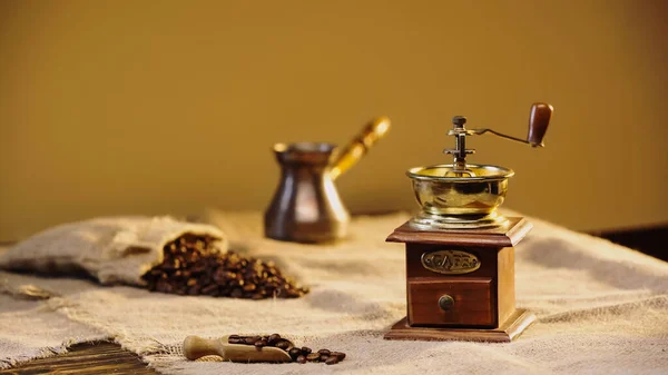 Vintage coffee grinder near blurred coffee beans and coffee pot — Fotografia de Stock