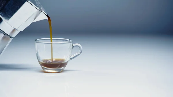 Espresso versando da caffettiera in tazza su bianco e grigio — Foto stock