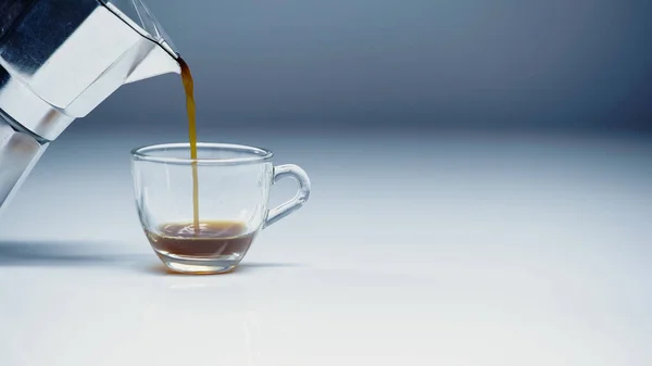 Espresso pouring from coffee maker into cup on white and grey — Foto stock