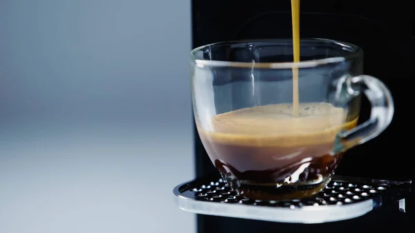 Close up of coffee maker pouring drink into cup on grey — Stockfoto