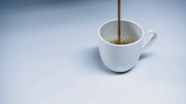 Hot espresso pouring into cup on white — Stock Photo
