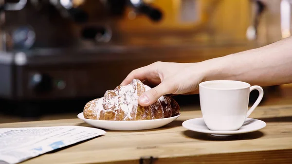 Vista recortada del hombre tomando croissant en la cafetería - foto de stock