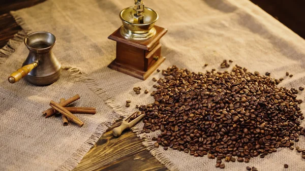 High angle view of cinnamon sticks near coffee beans on canvas — Fotografia de Stock