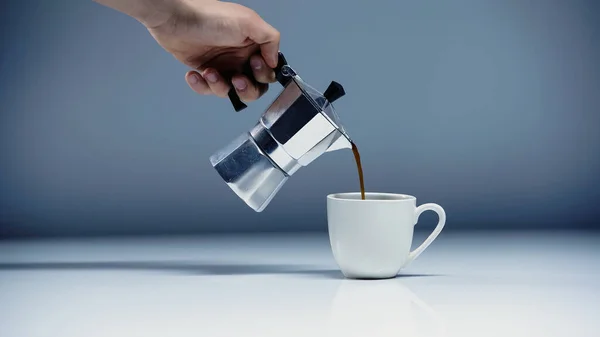 Cropped view of man pouring coffee into cup on white and grey — Stock Photo