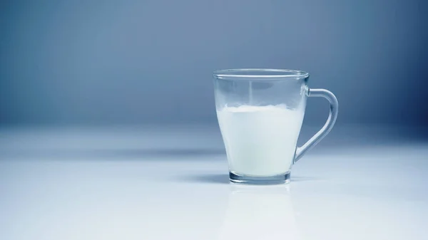Glass of fresh milk on white and grey — Stock Photo