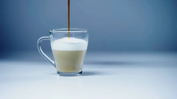 Coffee pouring into milk with foam on white and grey — Foto stock