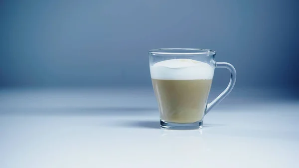 Café con leche con espuma blanca en vidrio sobre gris - foto de stock