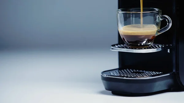 Automatic coffee maker pouring hot beverage into cup on gray — Stock Photo