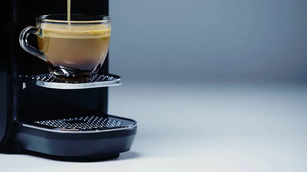 Automatische Kaffeemaschine gießt Heißgetränk in Glasschale auf grau — Stockfoto