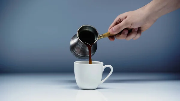 Cropped view of man pouring coffee into cup on white and grey — Stock Photo