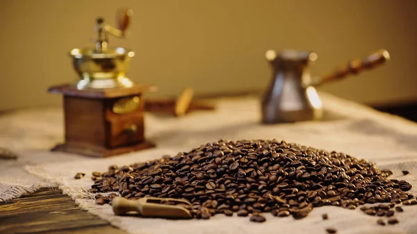Fresh coffee beans near blurred vintage coffee grinder — Foto stock