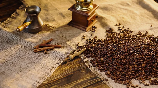 Canela varas perto de grãos de café na tela — Fotografia de Stock