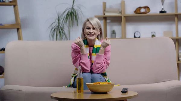 Feliz deporte fan mujer mostrando ganar gesto mientras ver la competencia en la televisión en casa - foto de stock