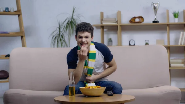 Fã de esporte emocionante assistindo campeonato em casa tv perto de cerveja e batatas fritas — Fotografia de Stock