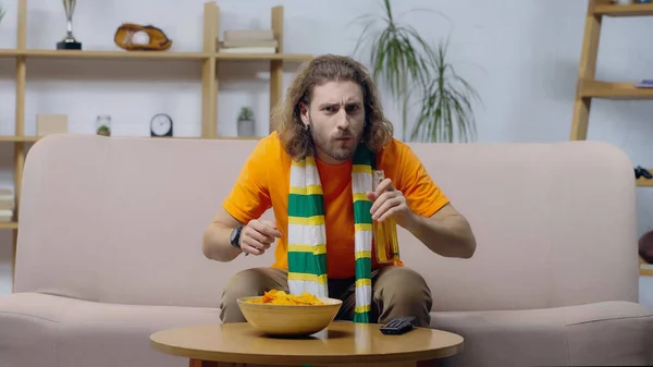 Worried man drinking beer while watching sport competition on tv at home — Stock Photo