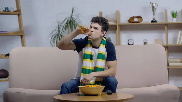 Worried sport fan drinking beer while watching championship on home tv — Stock Photo