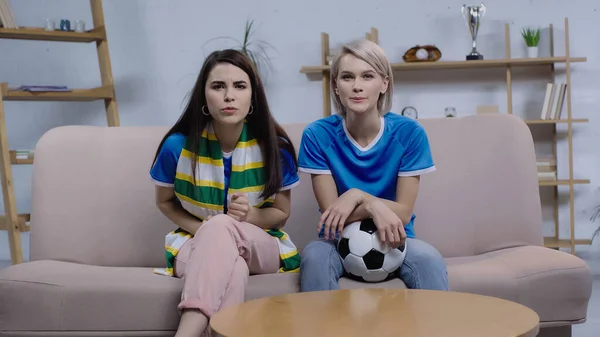 Konzentrierte Fußballfans, die zu Hause auf der Couch sitzen und die Meisterschaft im Fernsehen verfolgen — Stockfoto