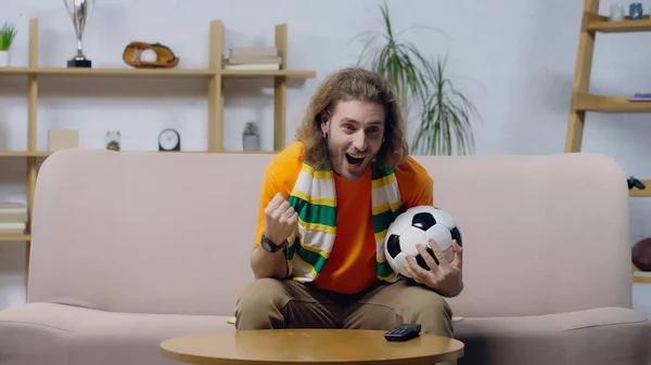 Excited football fan showing win gesture while watching championship on tv at home — Stockfoto