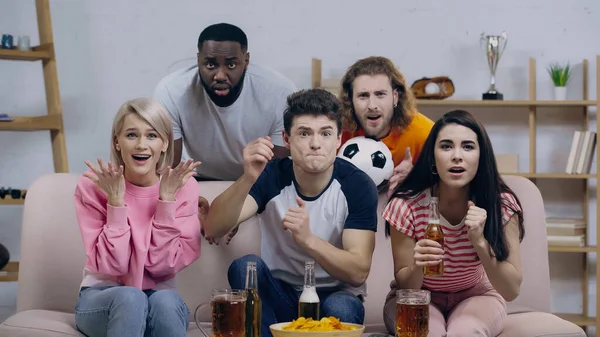 Emotional multicultural friends gesturing while watching football championship on tv at home — Fotografia de Stock