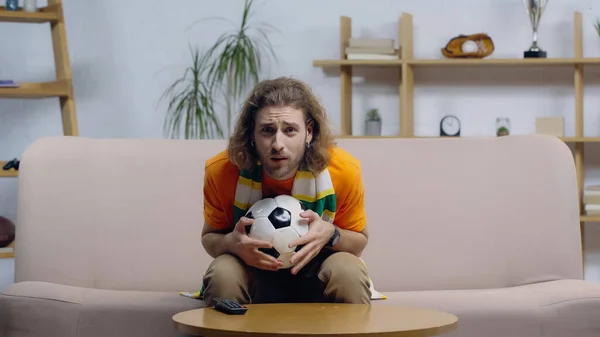 Nervous football fan sitting on couch at home and watching game on tv — Stock Photo