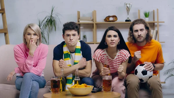 Nervous football fans holding clenched fists for luck while watching match on home tv — Stock Photo
