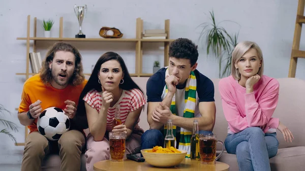 Обеспокоенные друзья жестом во время просмотра футбольного матча по телевизору возле пива и чипсов — стоковое фото