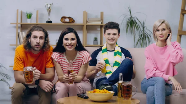 Happy sport fans drinking beer while watching sport championship on tv at home — Stock Photo