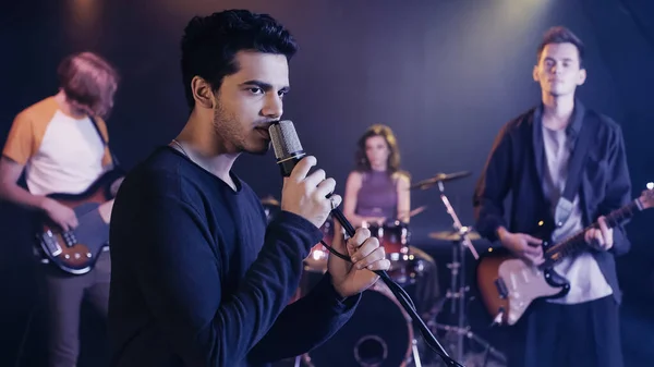 Cantante joven cantando canción con banda de música - foto de stock