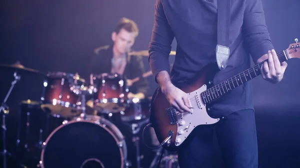 KYIV, UKRAINE - 30 DÉCEMBRE 2021 : guitariste rock jouant près du batteur flou sur scène — Photo de stock