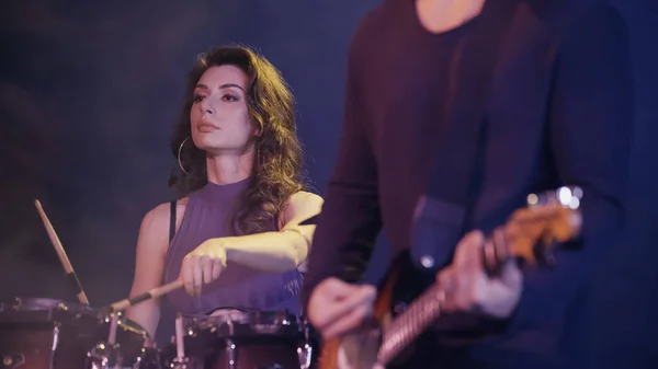 Curly drummer playing on drums near blurred rock guitarist — Foto stock