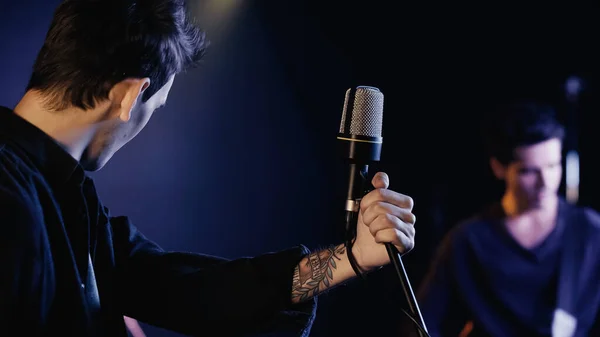 Tattooed singer near microphone and blurred musician on stage — Photo de stock