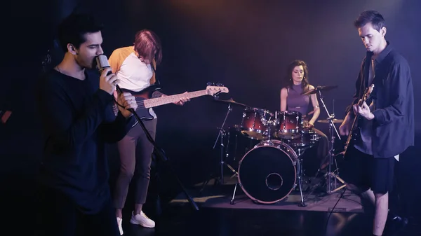 Young singer performing song with music band on stage — Stock Photo