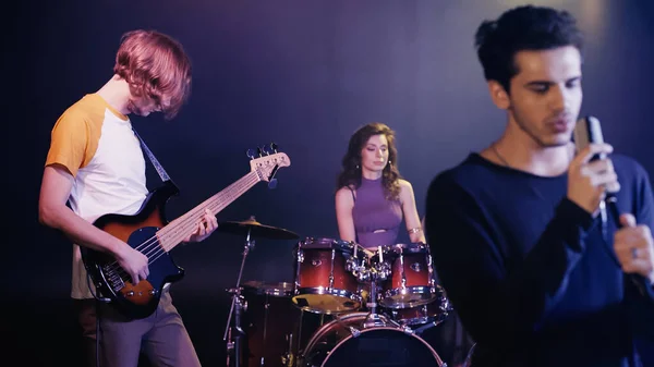 Blurred young singer performing song with music band on stage — Stock Photo