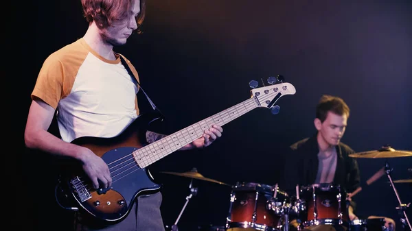 KYIV, UKRAINE - DECEMBER 30, 2021: rock guitarist playing near blurred drummer on stage - foto de stock