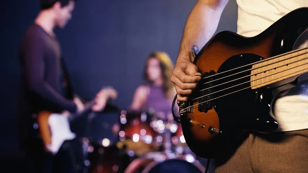 KYIV, UKRAINE - 30 DÉCEMBRE 2021 : vue recadrée d'un guitariste tatoué jouant avec un groupe flou sur scène — Photo de stock