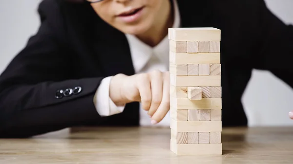 Cropped view of businesswoman playing blocks wood tower game isolated on grey — Foto stock