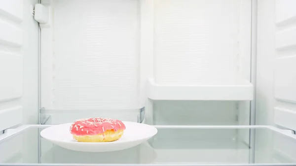 Sweet glazed doughnut on plate in fridge — Stock Photo