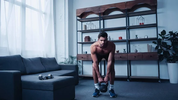 Muscular sportsman training with kettlebell at home — Fotografia de Stock