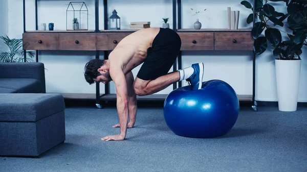 Vue latérale de l'entraînement sportif musculaire avec ballon de fitness à la maison — Photo de stock