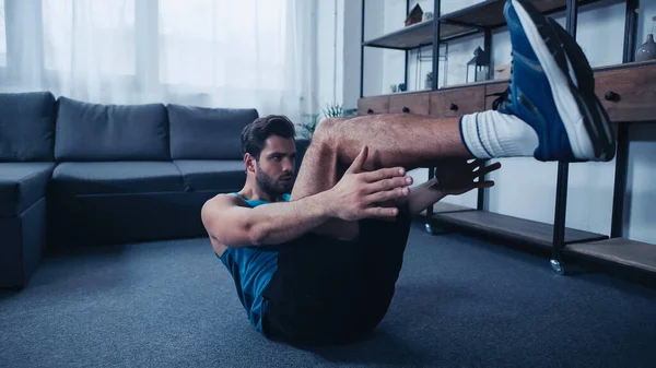 Bearded and sportive man working out on floor — Stockfoto