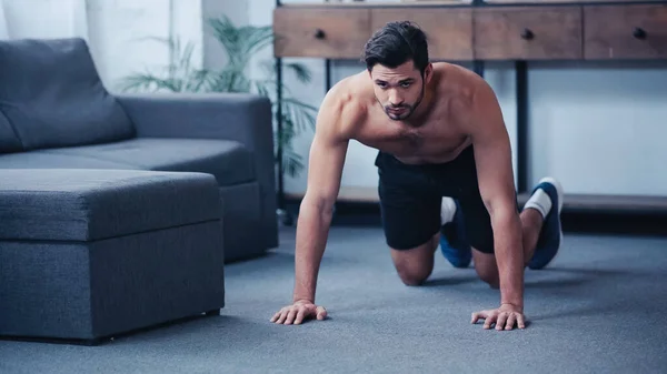 Muscular sportsman doing press ups on floor at home — Stock Photo