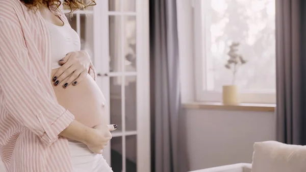 Обрезанный вид беременной женщины, касающейся живота дома — стоковое фото