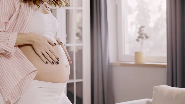 Cropped view of young pregnant woman touching belly at home — Stock Photo