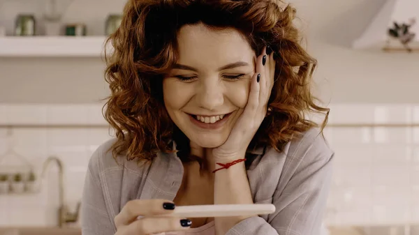 Positive curly woman holding pregnancy test at home — Fotografia de Stock