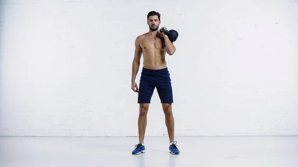 Deportista fuerte ejercicio con pesadas pesas cerca de la pared de ladrillo blanco - foto de stock