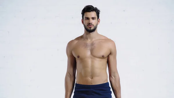 Shirtless and sportive man looking at camera near white brick wall — Stock Photo