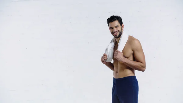 Desportista alegre segurando toalha e olhando para a câmera no branco — Fotografia de Stock