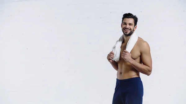 Desportista alegre segurando toalha e olhando para a câmera no branco — Fotografia de Stock